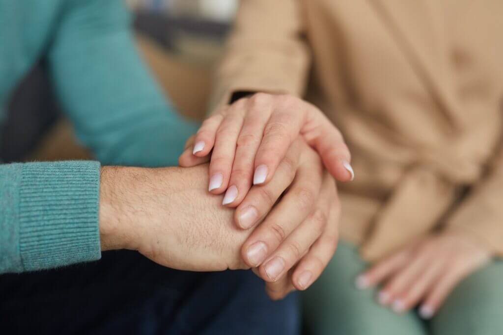 Two people holding hands in support